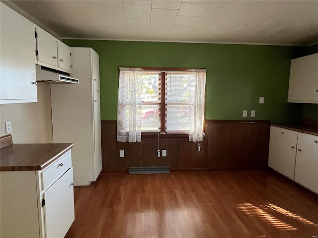 kitchen featuring wood walls, white cabinets, and hardwood / wood-style flooring