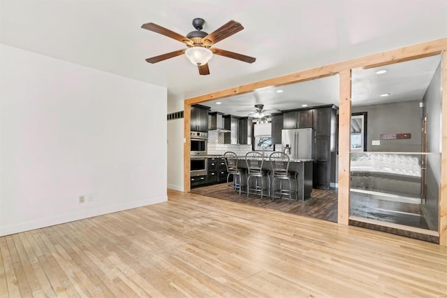 unfurnished living room with light wood-type flooring and ceiling fan