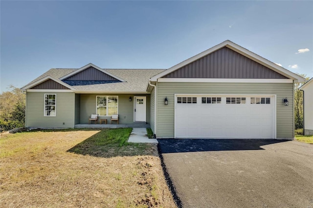 view of front of house featuring covered porch, a garage, and a front lawn