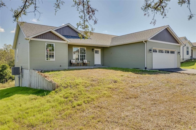 view of front of house featuring a porch, central AC, a garage, and a front lawn