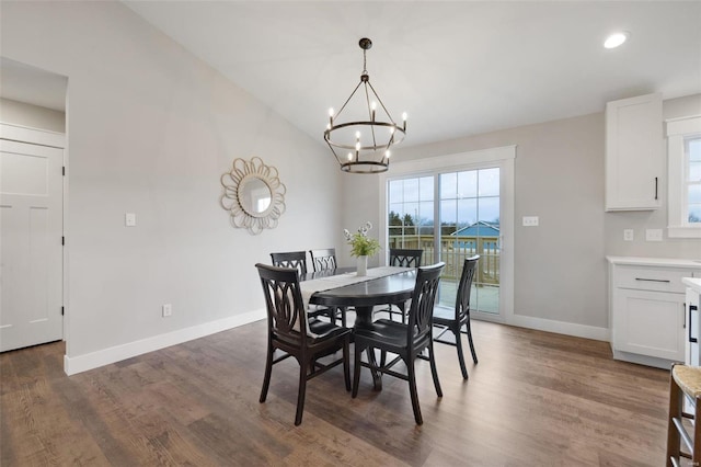 dining area with dark wood-type flooring, vaulted ceiling, and an inviting chandelier