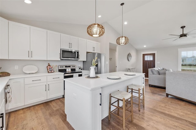 kitchen featuring white cabinetry, stainless steel appliances, pendant lighting, a breakfast bar, and a kitchen island