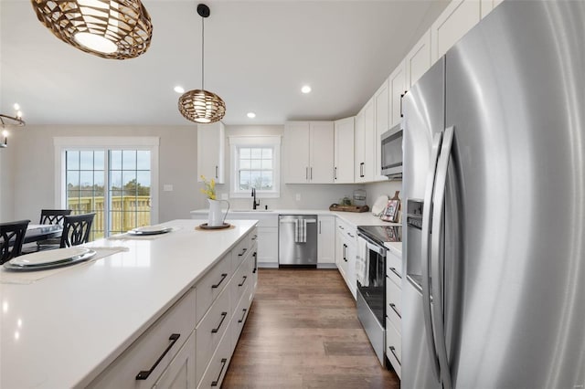 kitchen with sink, decorative light fixtures, white cabinetry, wood-type flooring, and stainless steel appliances