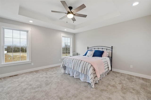 carpeted bedroom featuring a tray ceiling and ceiling fan