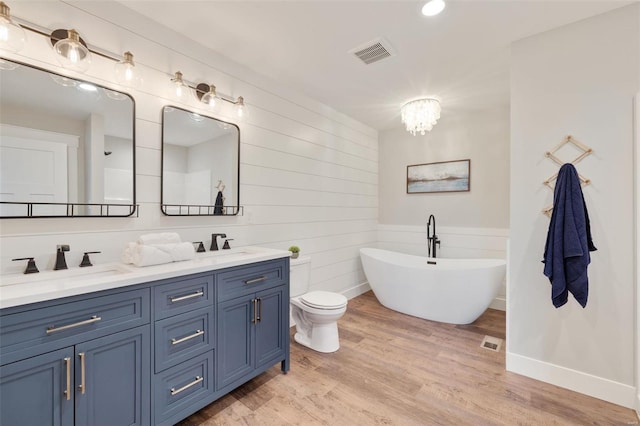 bathroom with vanity, hardwood / wood-style flooring, a washtub, toilet, and a chandelier