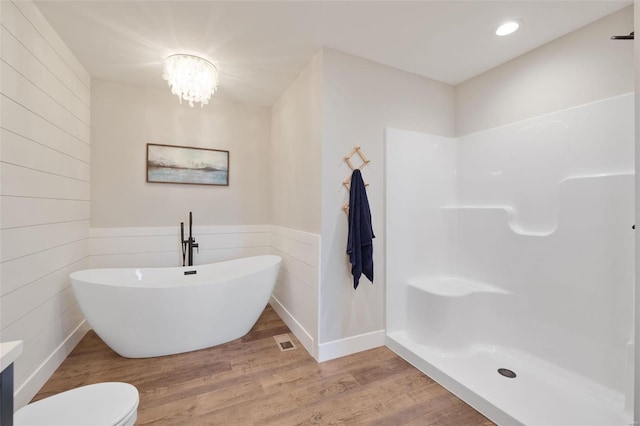 bathroom with a bathing tub, toilet, hardwood / wood-style floors, and a chandelier