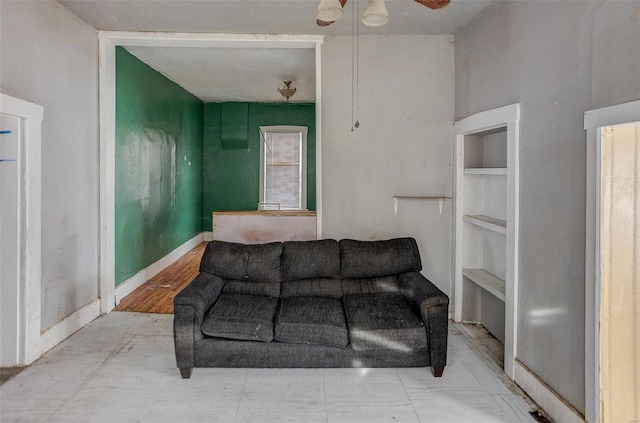 living room with built in shelves and ceiling fan