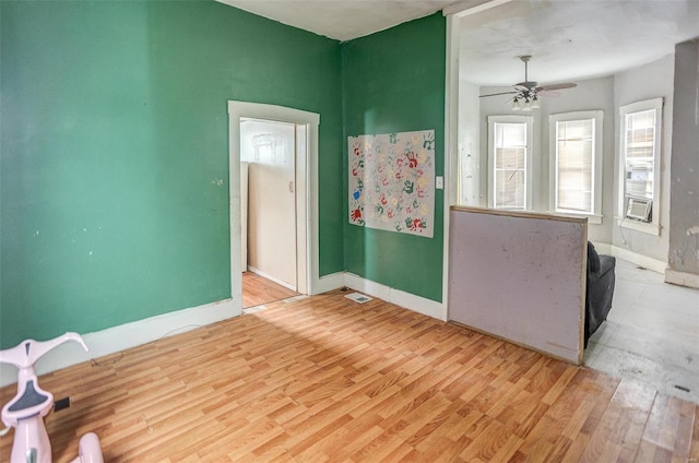 empty room featuring ceiling fan, cooling unit, and light hardwood / wood-style floors