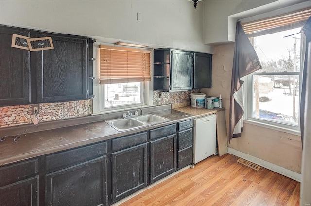 kitchen with white dishwasher, plenty of natural light, light wood-type flooring, and sink