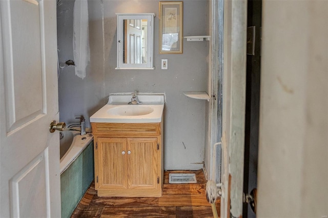 bathroom with vanity, wood-type flooring, and a tub to relax in