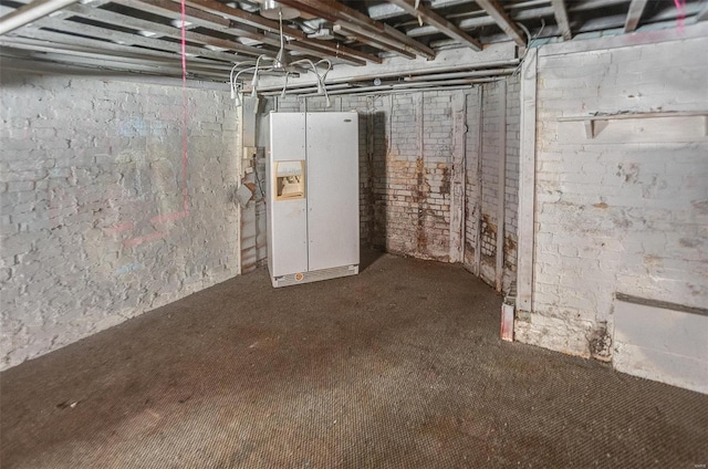 basement featuring white refrigerator with ice dispenser