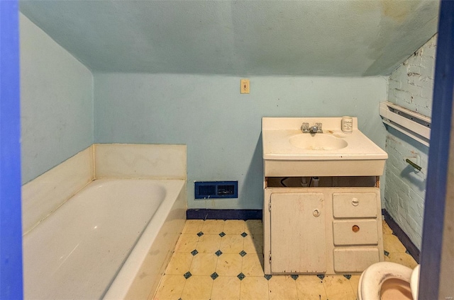 bathroom featuring sink, a bathtub, vaulted ceiling, and toilet