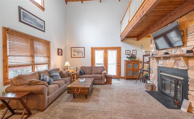 carpeted living room with a fireplace, a wealth of natural light, and a high ceiling