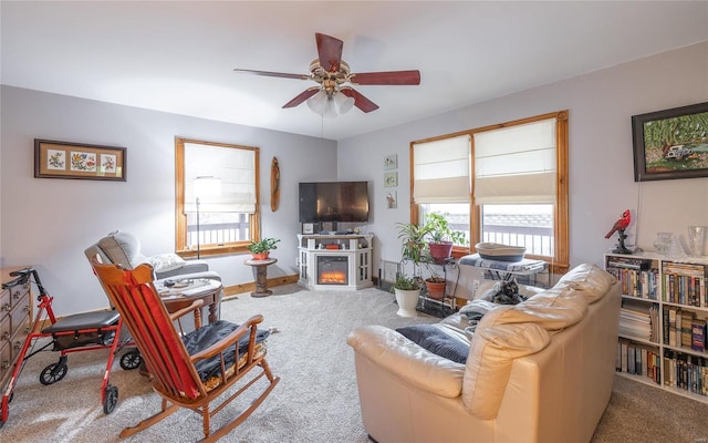 carpeted living room featuring a fireplace and ceiling fan