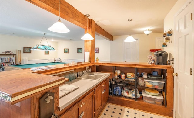 interior space with kitchen peninsula, decorative light fixtures, beamed ceiling, and sink