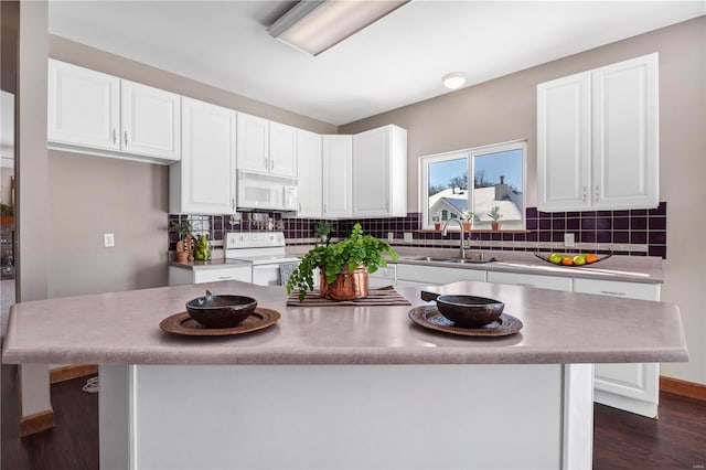 kitchen with sink, white appliances, a center island, and white cabinets