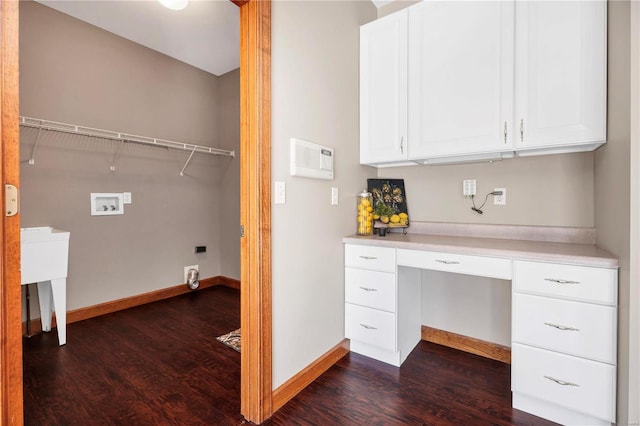 unfurnished office with built in desk, dark wood-type flooring, and sink