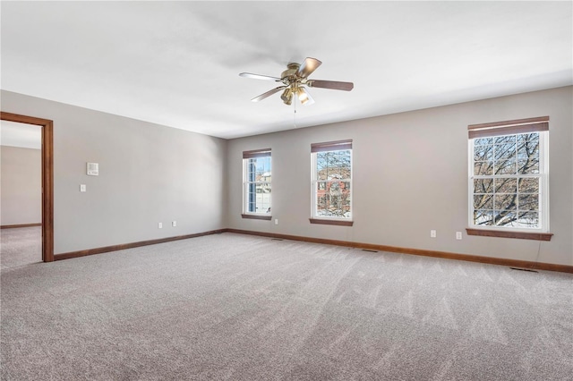 carpeted empty room featuring ceiling fan and a wealth of natural light