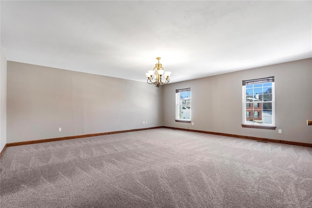 carpeted spare room with a notable chandelier