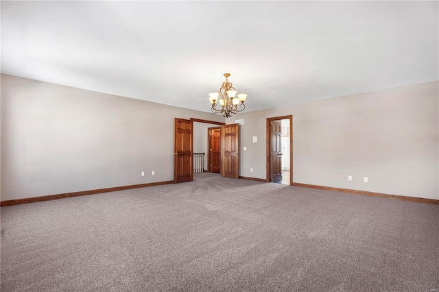 empty room featuring a notable chandelier and carpet