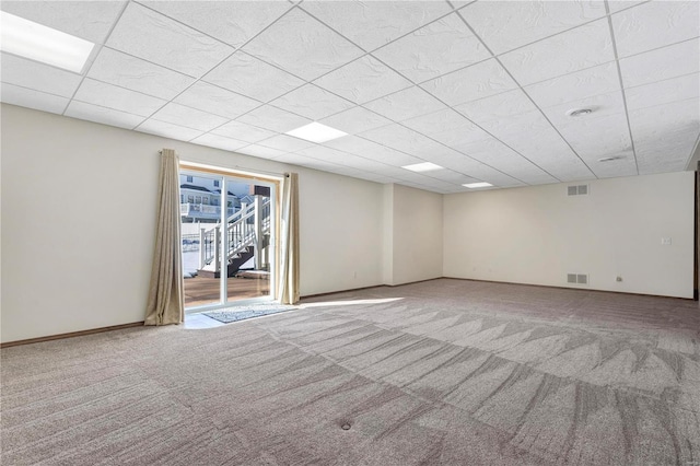 unfurnished room featuring light colored carpet and a drop ceiling