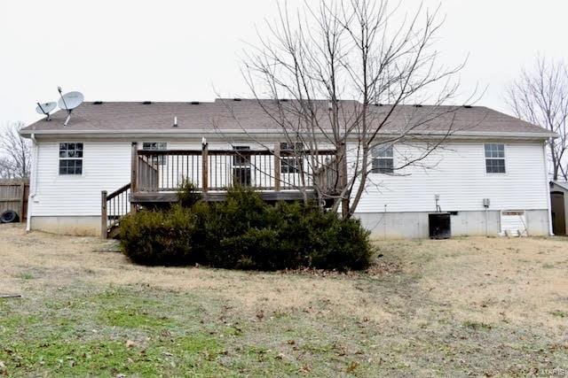 back of property with a deck and a yard