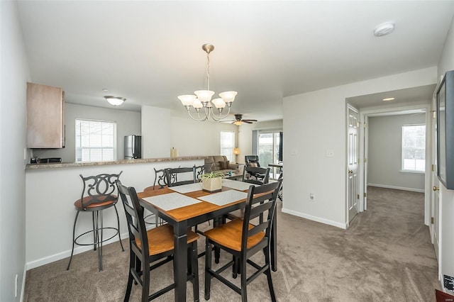 carpeted dining space with ceiling fan with notable chandelier