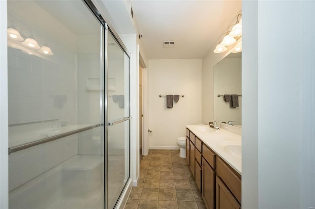 bathroom with vanity, toilet, and a shower with door