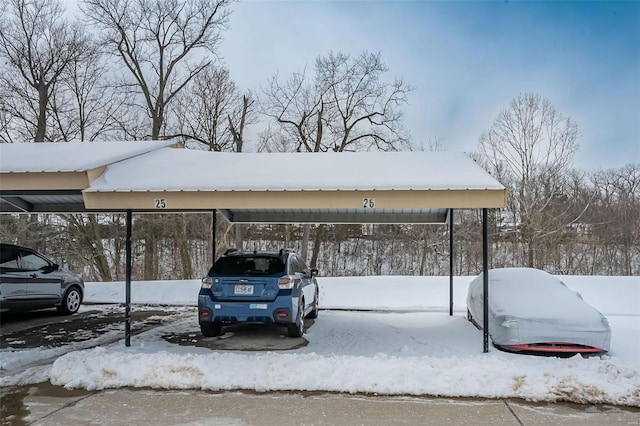 snow covered parking area with a carport