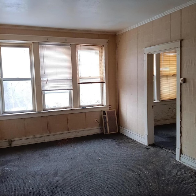 carpeted empty room with a baseboard heating unit and crown molding