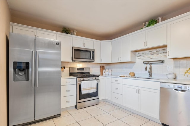 kitchen with light tile patterned floors, appliances with stainless steel finishes, white cabinets, and sink