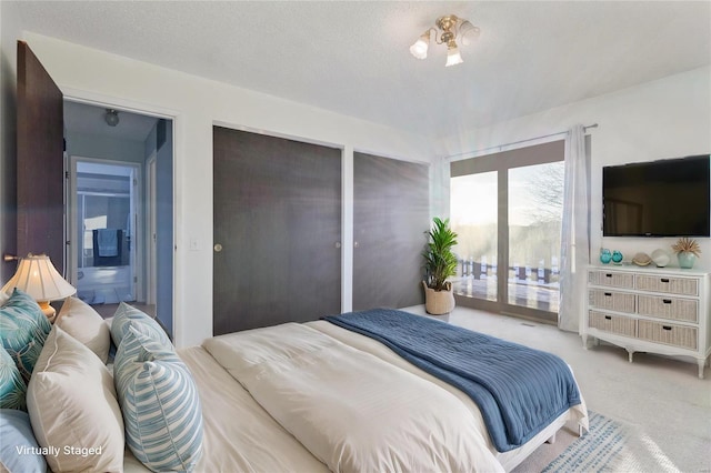 bedroom featuring a textured ceiling, connected bathroom, carpet floors, and access to outside