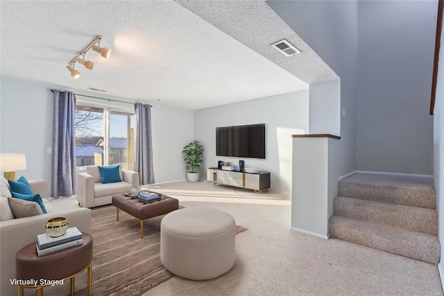 carpeted living room featuring a textured ceiling and track lighting