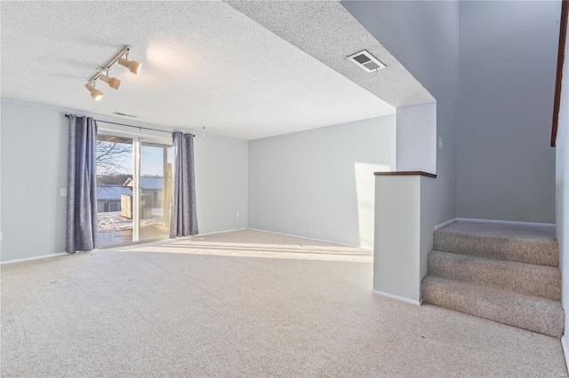 spare room with a textured ceiling, carpet flooring, and rail lighting