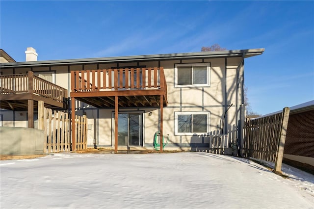 snow covered rear of property with a wooden deck