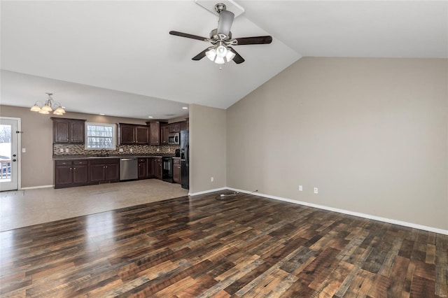 unfurnished living room featuring ceiling fan with notable chandelier, sink, dark wood-type flooring, and vaulted ceiling