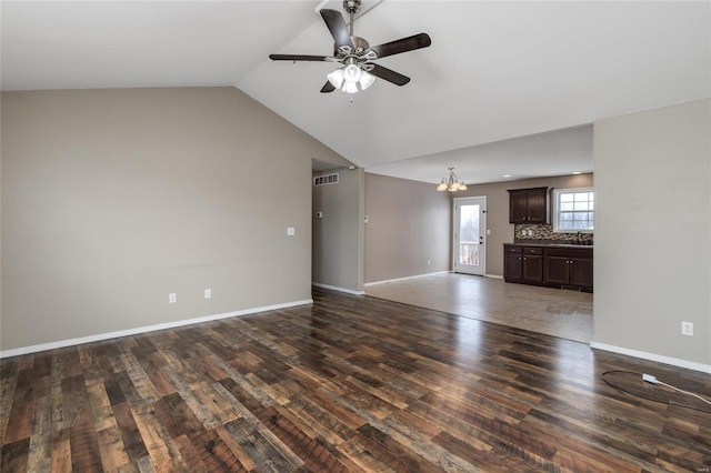 unfurnished living room with ceiling fan with notable chandelier, vaulted ceiling, and dark wood-type flooring