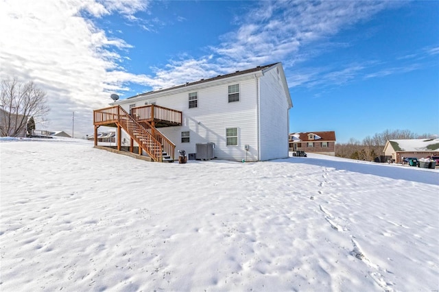 snow covered house with a wooden deck and cooling unit