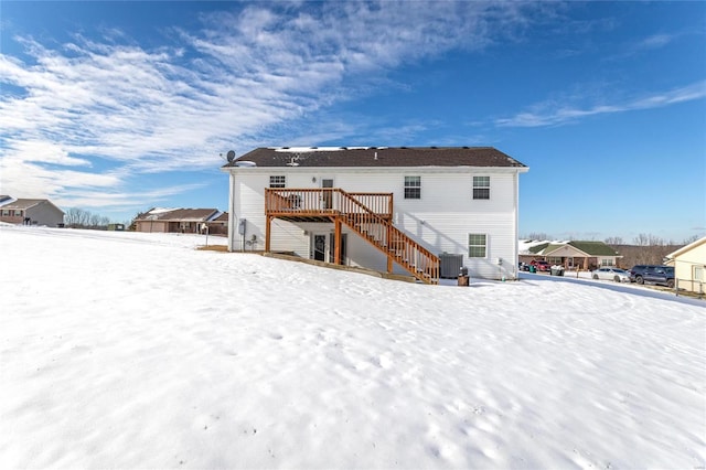 snow covered back of property with a wooden deck and central AC unit