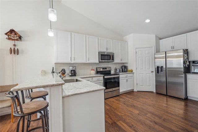 kitchen featuring appliances with stainless steel finishes, tasteful backsplash, a kitchen bar, decorative light fixtures, and kitchen peninsula