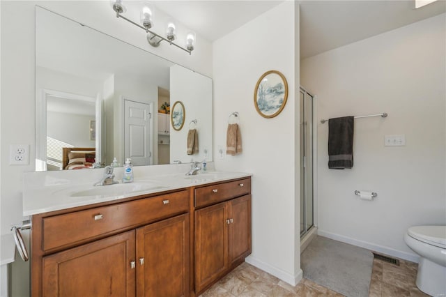 bathroom with toilet, vanity, and a shower with shower door