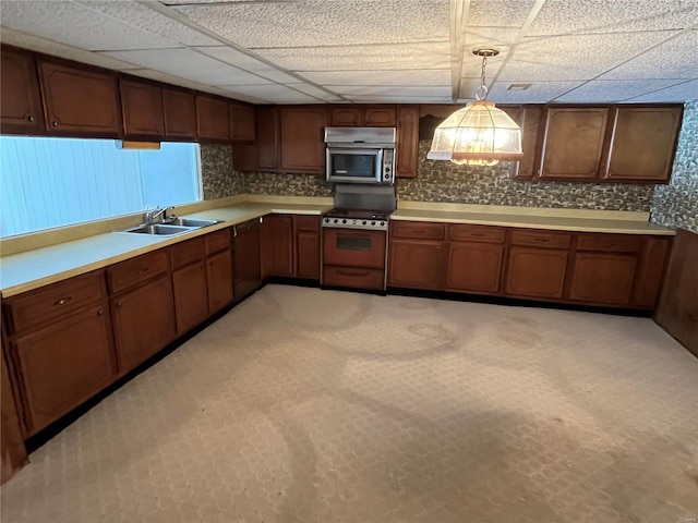 kitchen with a paneled ceiling, decorative light fixtures, stainless steel appliances, and sink