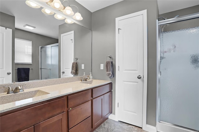 bathroom with a shower with door, vanity, and tile patterned floors