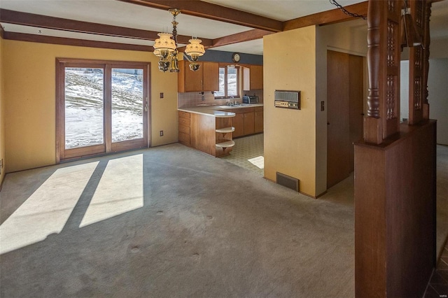 interior space featuring a healthy amount of sunlight, beam ceiling, pendant lighting, and a notable chandelier