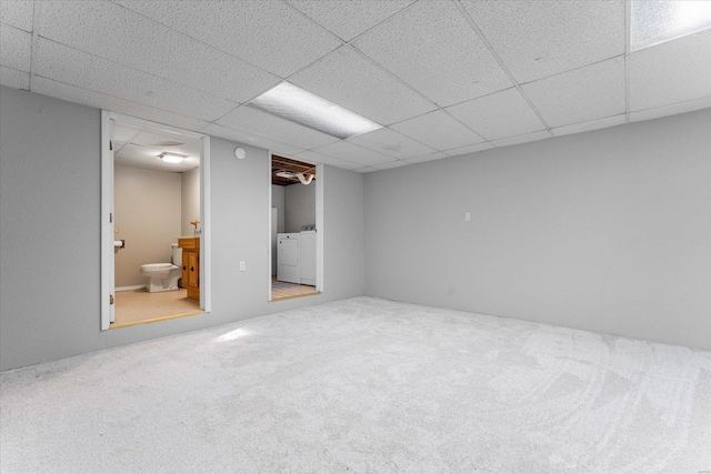 basement with carpet floors, washing machine and clothes dryer, and a paneled ceiling