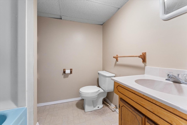 bathroom with vanity, a bathtub, toilet, and a drop ceiling