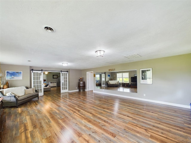 unfurnished living room with a textured ceiling, a barn door, and hardwood / wood-style flooring