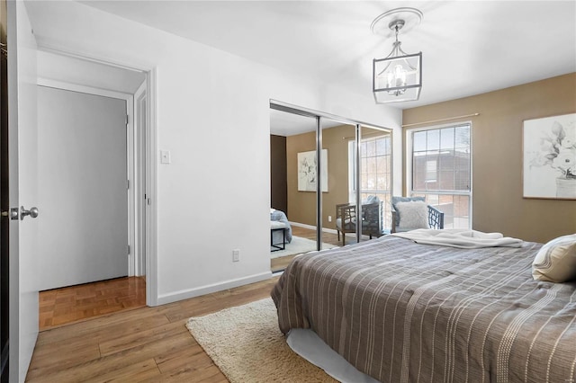 bedroom featuring wood-type flooring, a closet, and a notable chandelier