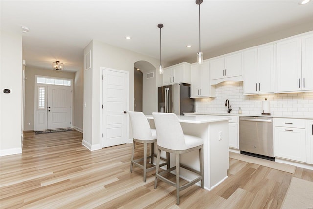 kitchen featuring a kitchen island, pendant lighting, sink, white cabinetry, and stainless steel appliances