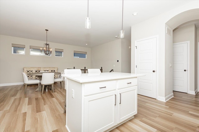 kitchen featuring light wood-type flooring, white cabinets, hanging light fixtures, and a center island